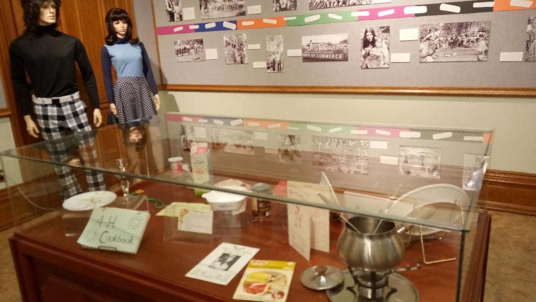 Display cases show icons from 1973. In the background of this photo is a sampling of fashion choices from that time. Photo: Merced Courthouse Museum